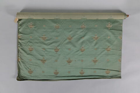 Rouleau de tissu d'ameublement à fond vert décoré d'étoiles et de vases à têtes de béliers blancs et or, image 1/3