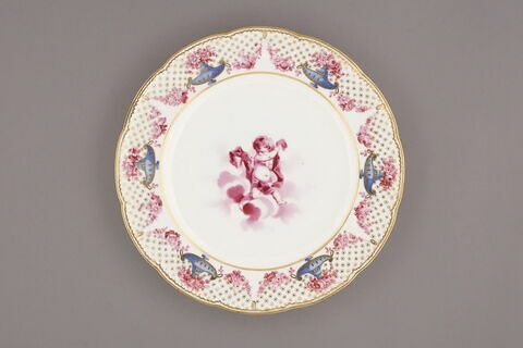 Assiette d'une série de quarante et une (R 510 à 549 bis); du service en pâte tendre blanche décorée de vases fleuris et d'amour en camaïeu rose et à bordure oeil de perdrix doré (R 489 à 549)