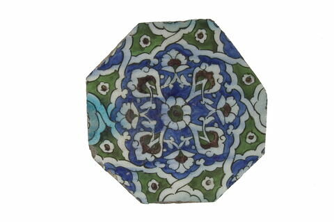 Carreau octogonal à motif étoilé contenant un motif floral centré