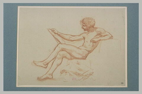 Jeune homme, assis jambes croisées, tenant un carton et un compas